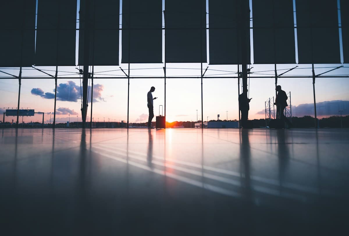 Travellers with luggage in an airport terminal at sunset